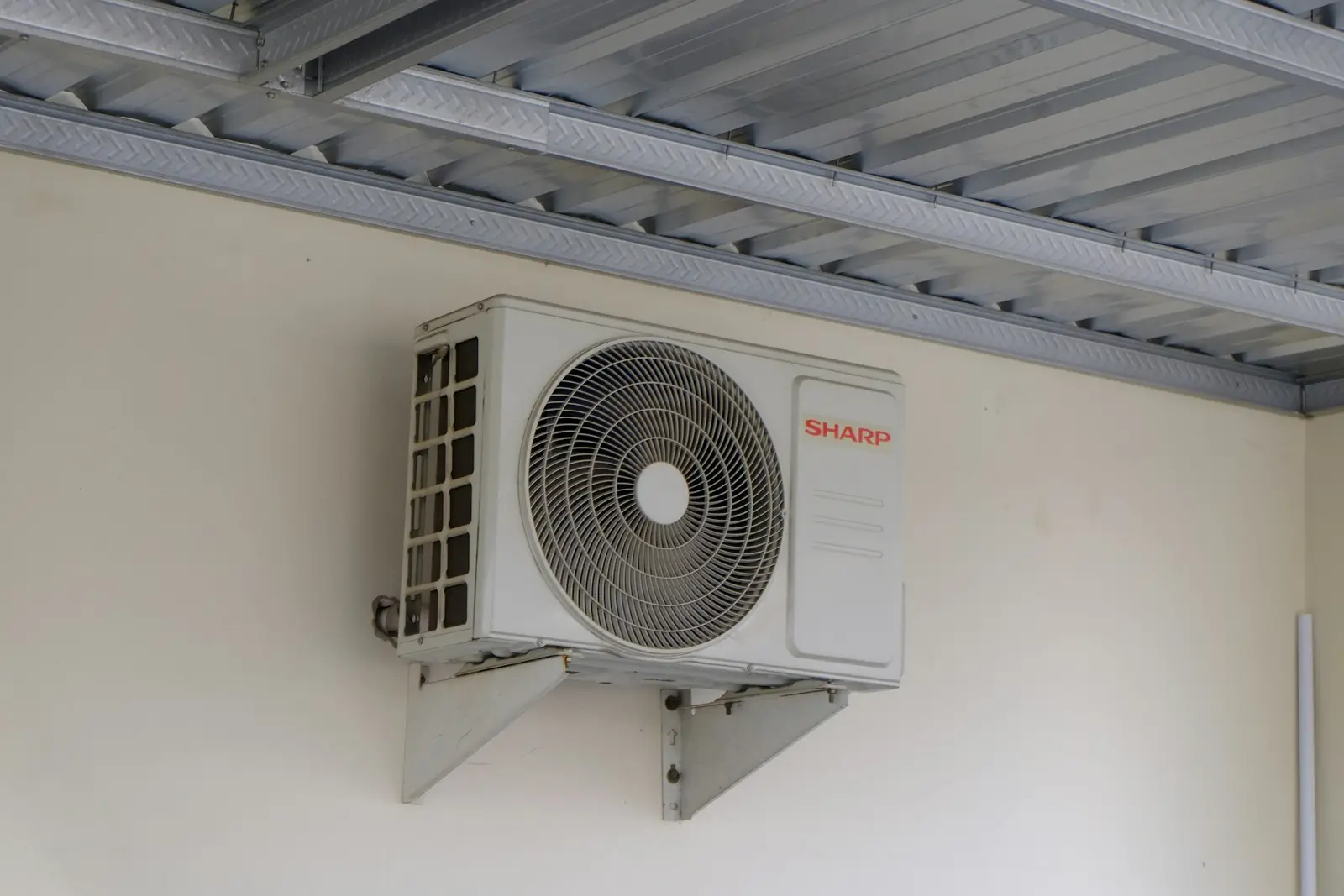 Unidad exterior de aire acondicionado instalada en una pared con soportes